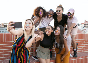 Group of friends wearing colorful reef safe Nöz sunscreen on their noses while taking a selfie.